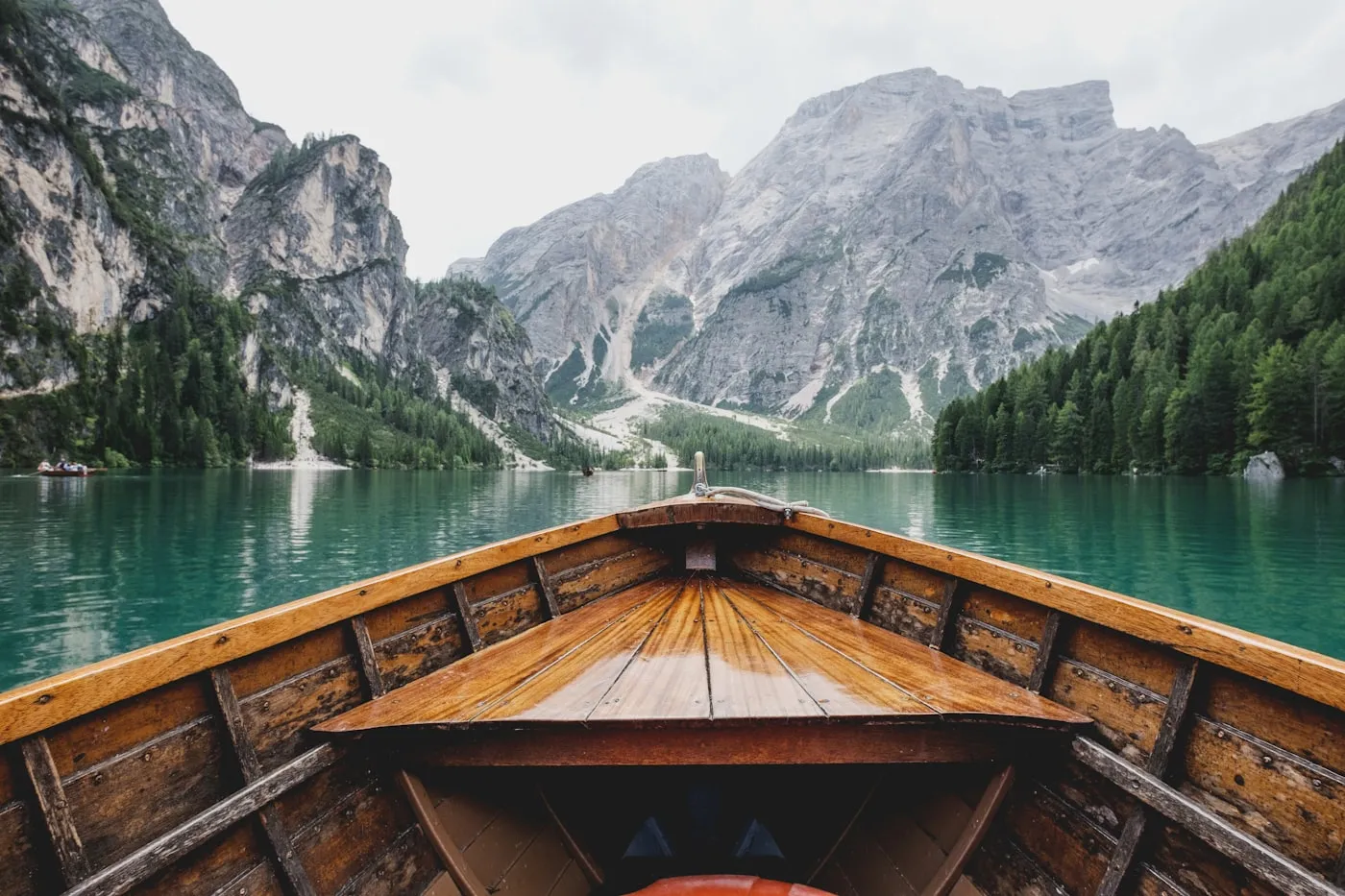 View from a wooden rowing boat across the green water of Lago di Braies