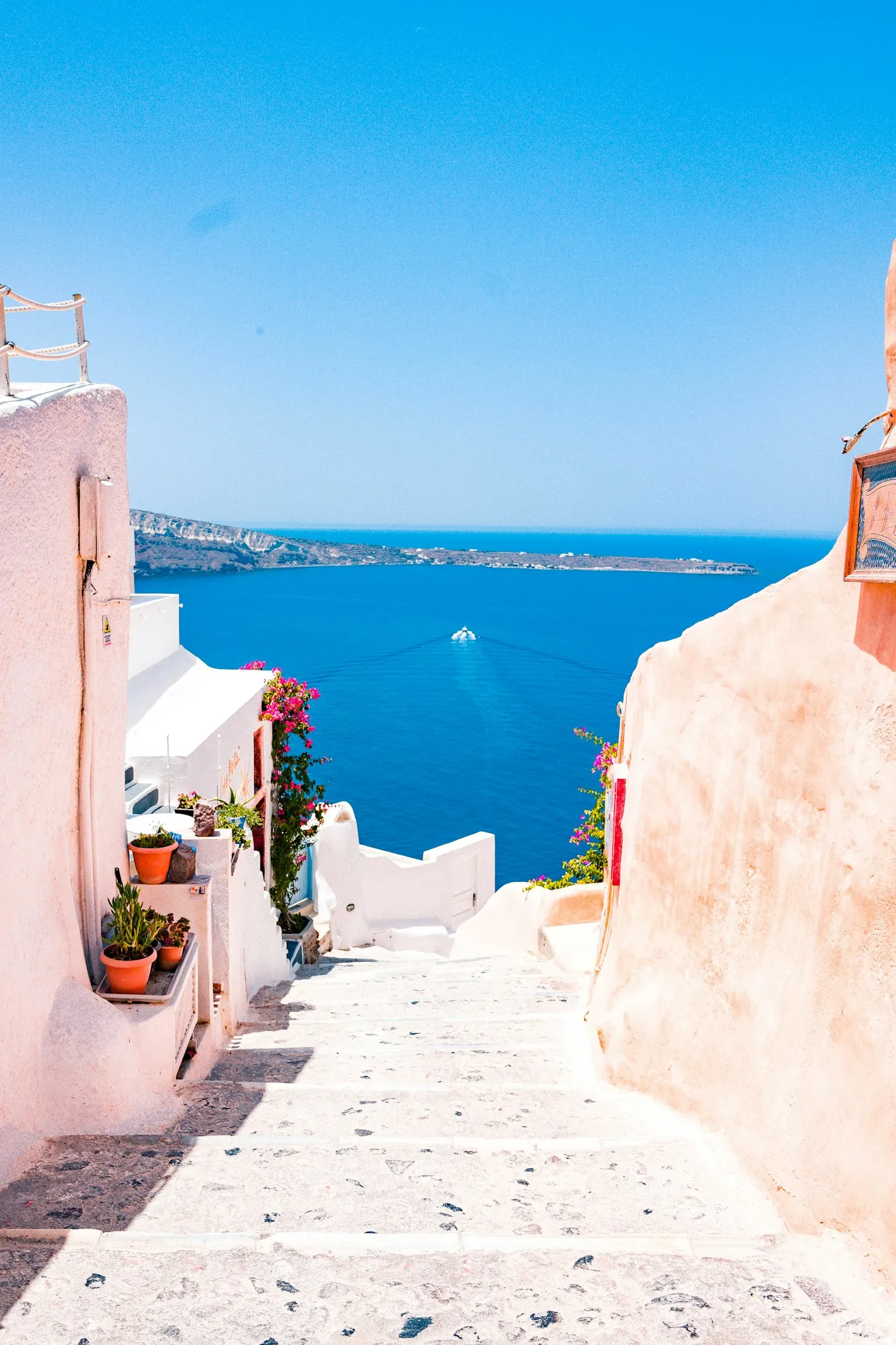 Whitewashed steps descending between cliff houses toward the Aegean, Santorini